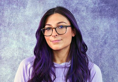 Young woman with purple hair wearing glasses for product modeling