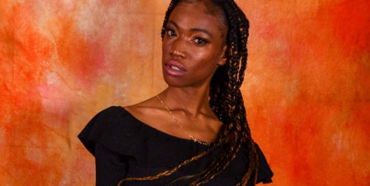 Jennypher, models, Haitian model in black shirt against orange backdrop