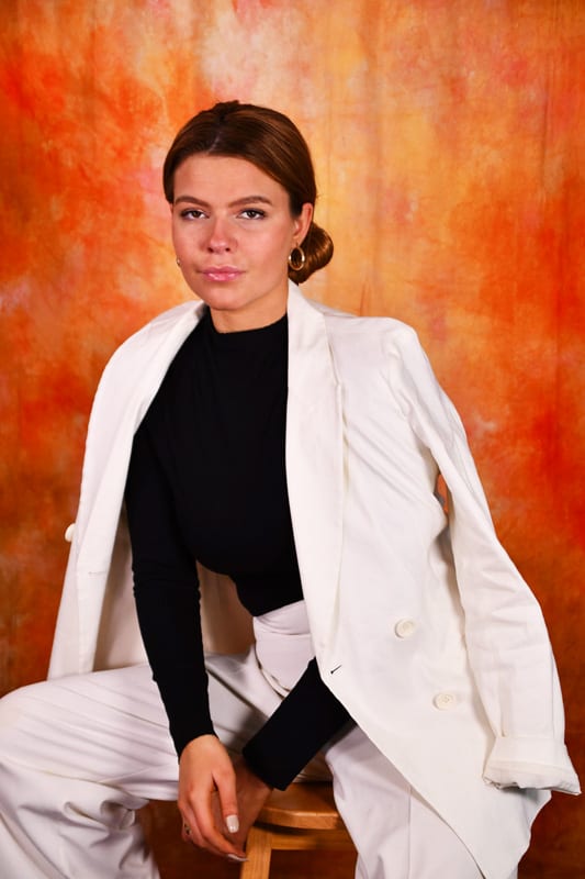 Leah - redhead model in black with white jacket, orange background