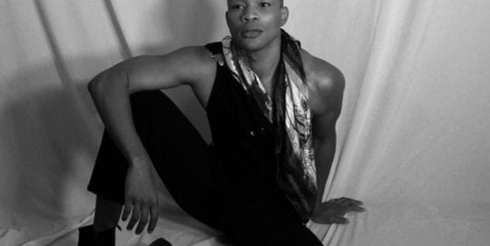 Model - Shaun - tall black man sitting on floor in black and white