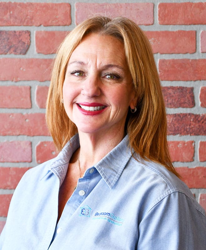 business professional headshot of older blonde woman against brick wall