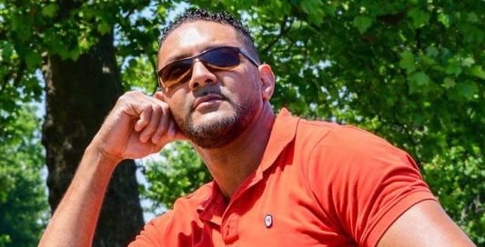 male model in red polo sitting at a table in the park