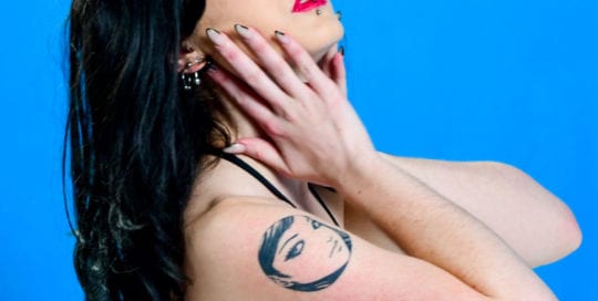 alt goth model side profile bust shot on blue background