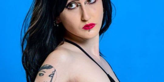 side profile of goth model. Alt model with black hair and piercings