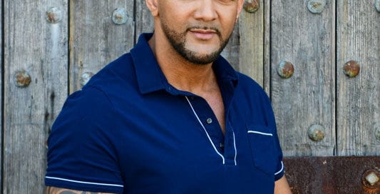 Male model Olivier in a blue polo against outdoor wood panels