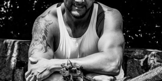 male model leaning over antique artillery in black and white