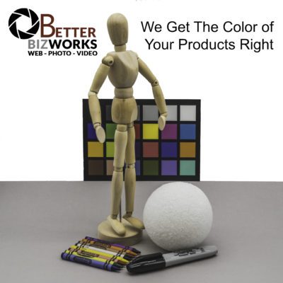 Product Photography test shot. Posable wooden mannequin next to crayons, a marker, and a foam ball. Color card for photography in the background. Better Biz Works logo in corner. 